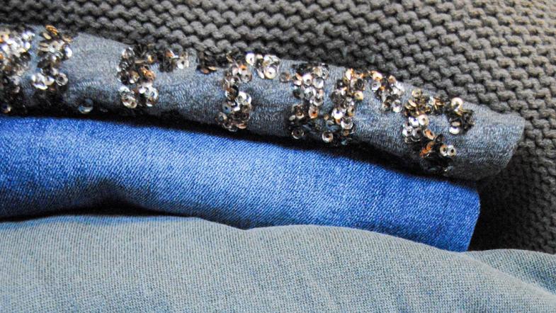 Stapel aus Hosen und Pullovern in blau und grau