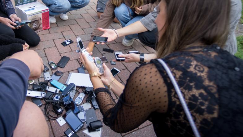Jugendliche begutachten einen Haufen alter Handys
