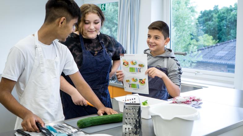 zwei Jungen und ein Mädchen in der Schulküche
