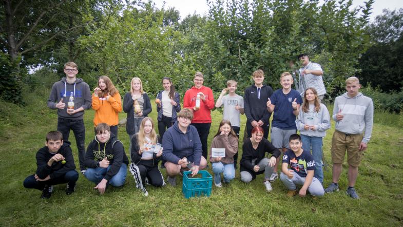 Schülergruppe vor Apfelbäumen 
