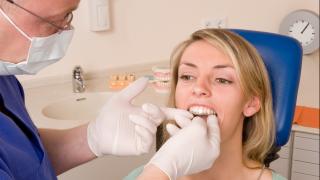 Frau beim Zahnarzt bekommt eine Aufbisschiene eingesetzt gegen Zähneknirschen 