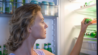 Frau am geöffneten Kühlschrank