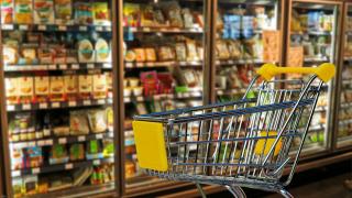 Leerer Einkaufswagen vor Supermarkt-Kühlschränken