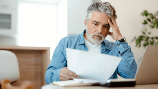 Ein Mann blickt fassungslos auf ein Blatt Papier