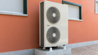 Eine Wärmepumpe auf einem eigenen Fundament vor einer Hauswand