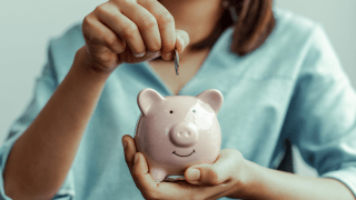 ein Kind steckt eine Münze in ein Sparschwein