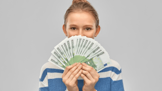 Jugendliche mit Geldscheinen vorm Gesicht