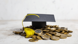 Absolventenhut liegt auf einem kleinen Haufen Euro und Cent Münzen