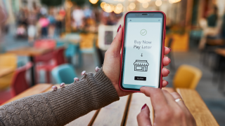 Ein Smartphone wird in den Händen gehalten. Auf dem Display steht Buy now, pay later