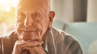 älterer Mann schaut betrübt in die Kamera