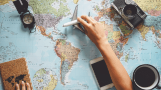 Eine Person zieht eine Spielzeugflugzeug über eine Landkarte