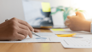 zwei Personen sitzen sich an einem Tisch gegenüber und gehen Energierechnungen durch