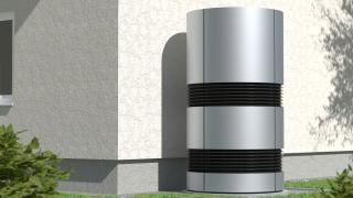 Eine Luft-Wasser-Wärmepumpe steht neben einer Hauswand im Garten.