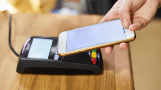 Ein Smartphone wird zur Bezahlung an eine Kartenlesegerät gehalten
