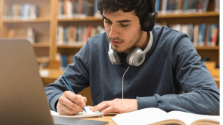 Ein Schüler sitzt in einer Bibliothek vor einem Laptop und lernt