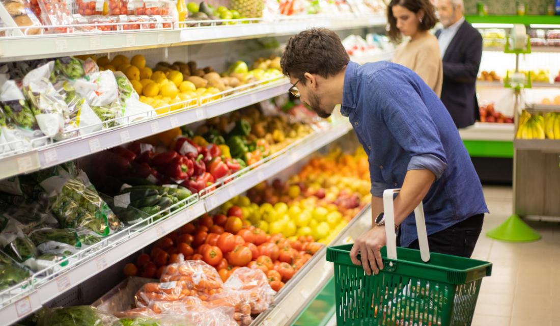 Mann mit Einkaufskorb im Supermarkt vor der Obstauswahl