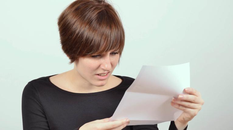 Frau blickt entsetzt auf Brief